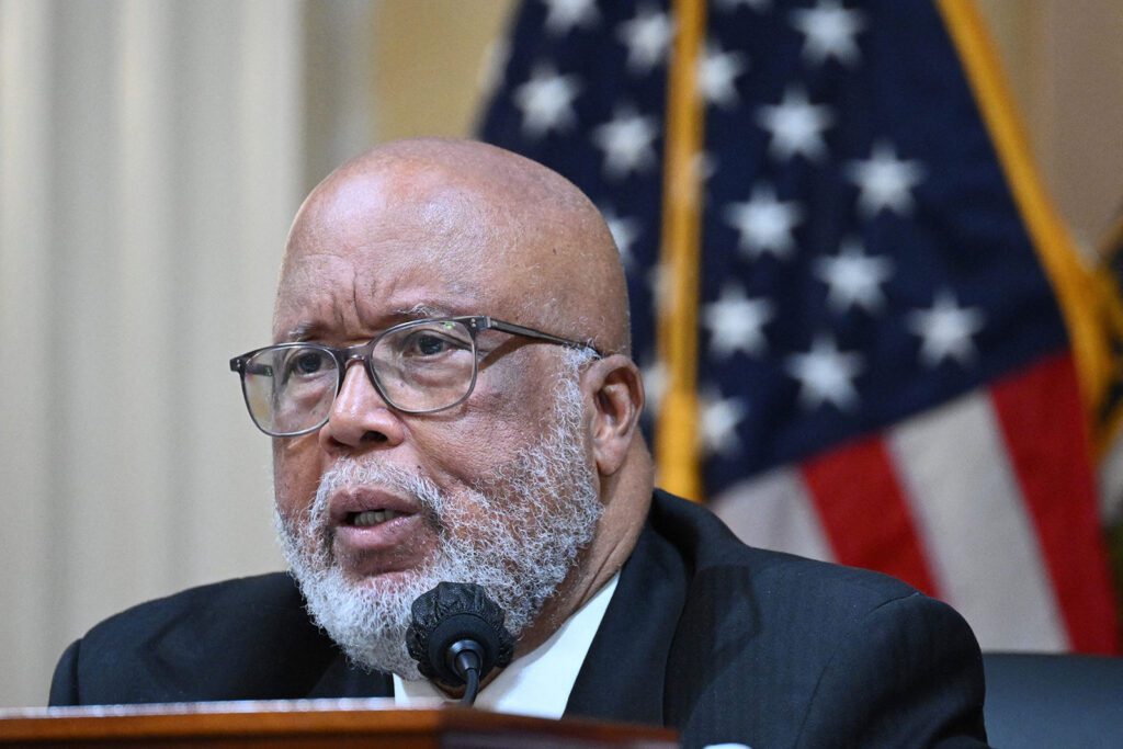 A man with glasses is speaking at a microphone.