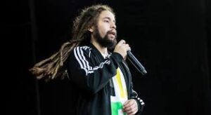 A man with dreadlocks is holding a microphone.
