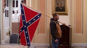 A man holding a confederate flag in front of a portrait.