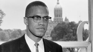 A man in suit and tie standing next to trees.