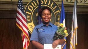 A woman in uniform holding flowers and a paper.