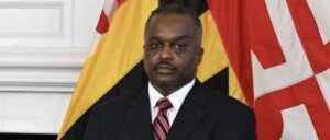 A man in a suit and tie standing next to an american flag.