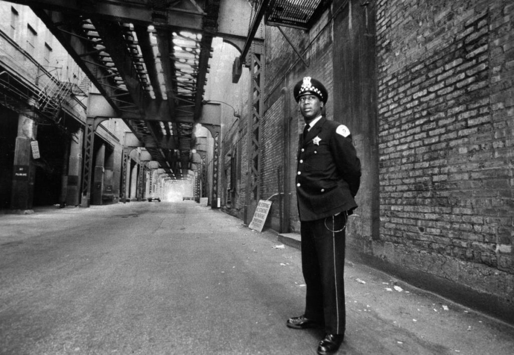 A police officer standing in the middle of an alley.