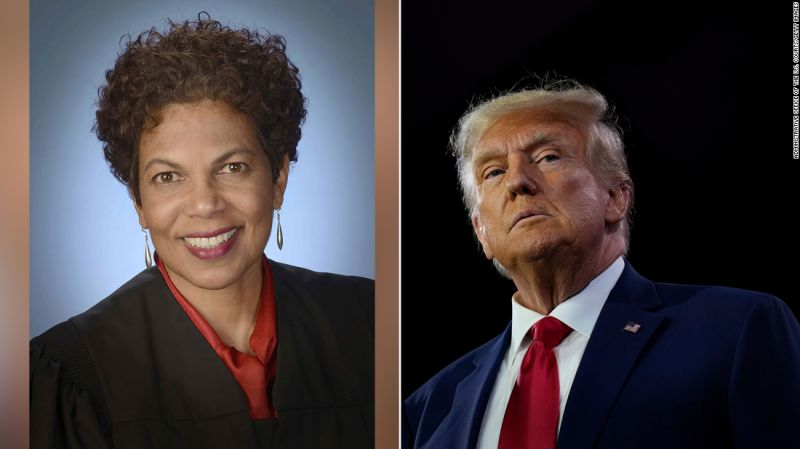 A woman in black jacket next to an image of president trump.