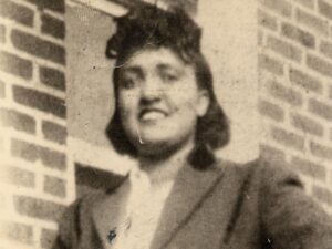 A woman in a suit and tie smiling for the camera.