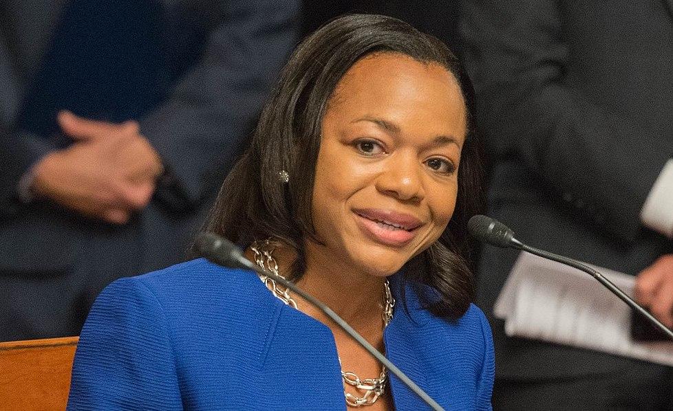 A woman in blue jacket holding a microphone.