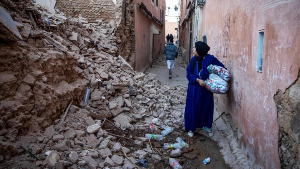 A woman in blue carrying a bag of food.