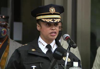 A woman in uniform is speaking at a podium.