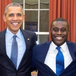 Two men in suits posing for a picture.