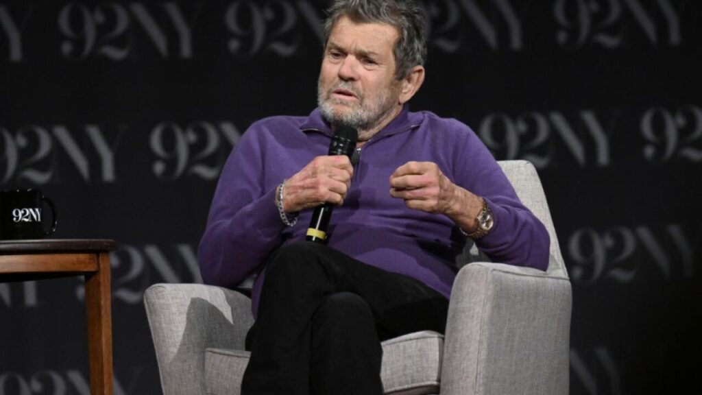 A man sitting in a chair holding a microphone.