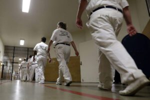 A group of people in white uniforms walking down the hall.