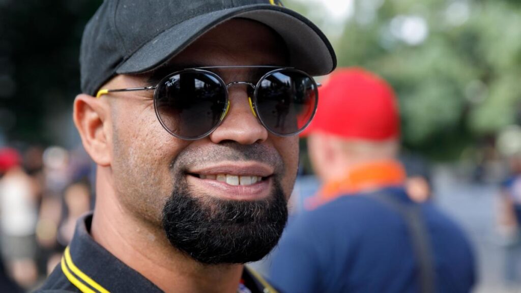 A man with beard and sunglasses smiling for the camera.