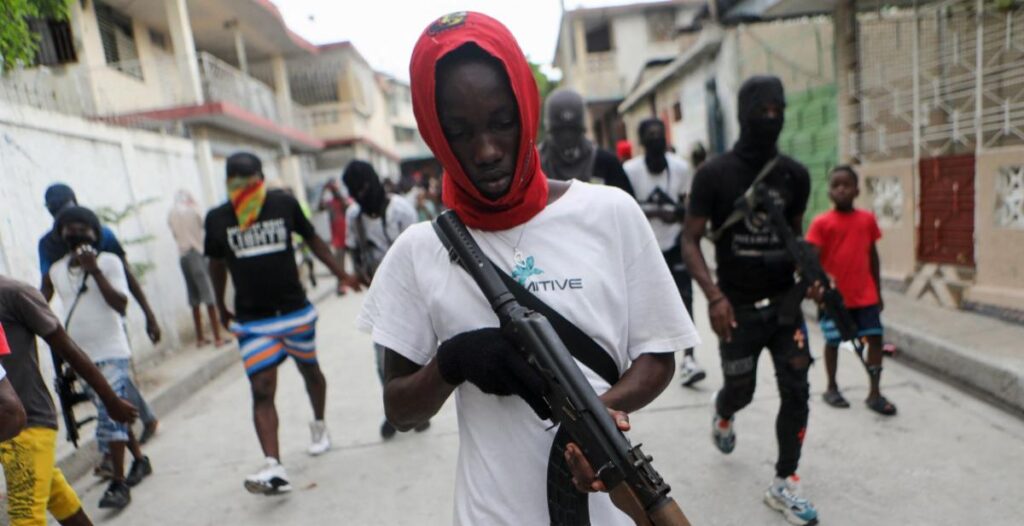 A man in a red hood holding an ak 4 7.