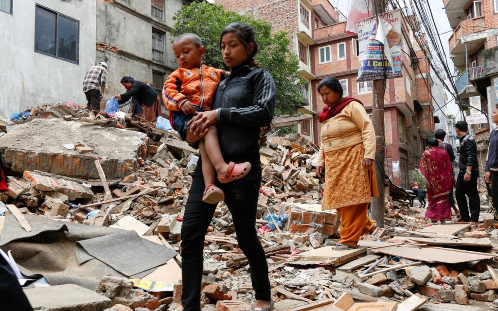 A woman holding her child in the rubble of a building.