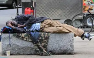 A person sleeping on the ground in front of a building.