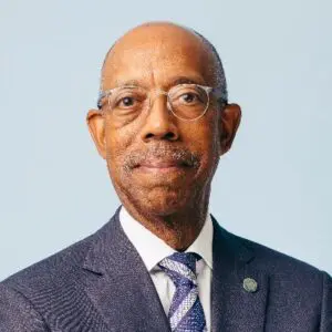 Man in suit and glasses smiling.