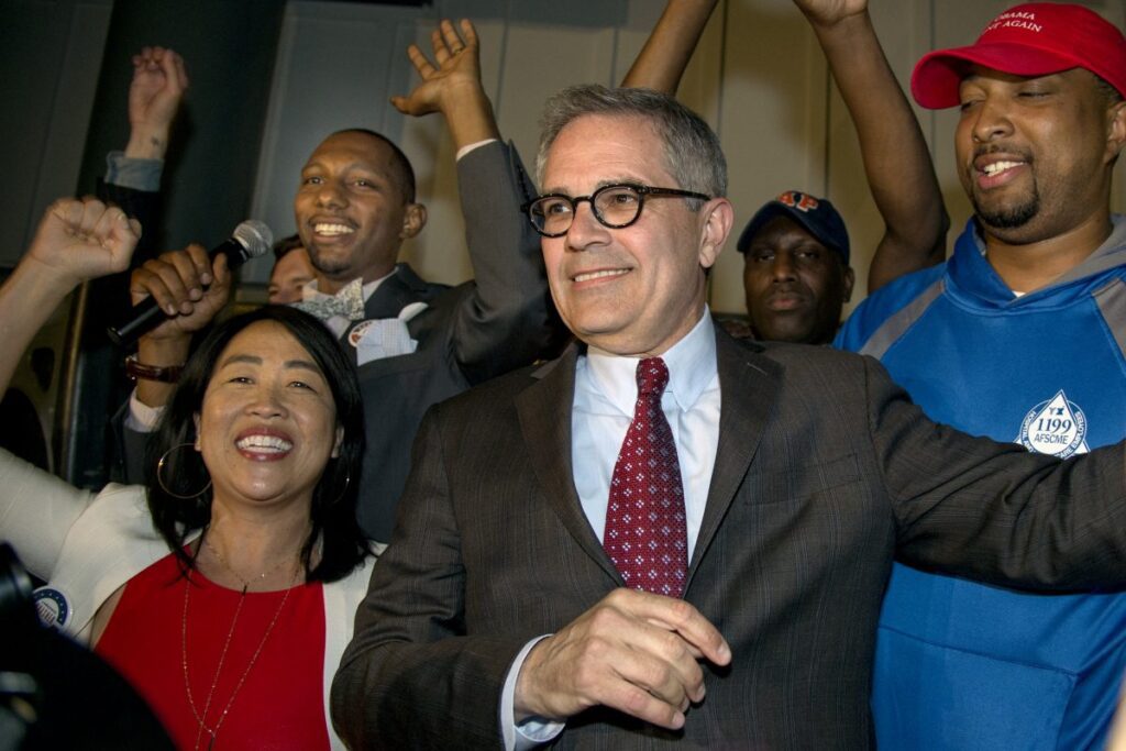 Politician in suit with supporters at rally.