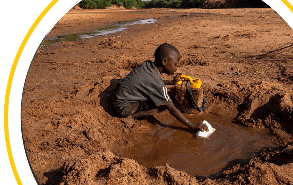 Boy attempting to drink water from muddy well