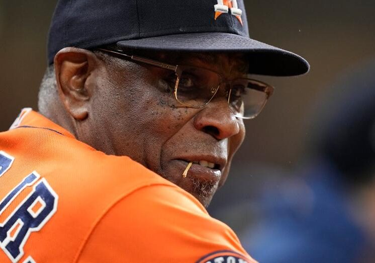 A close up of an older man wearing glasses and a hat