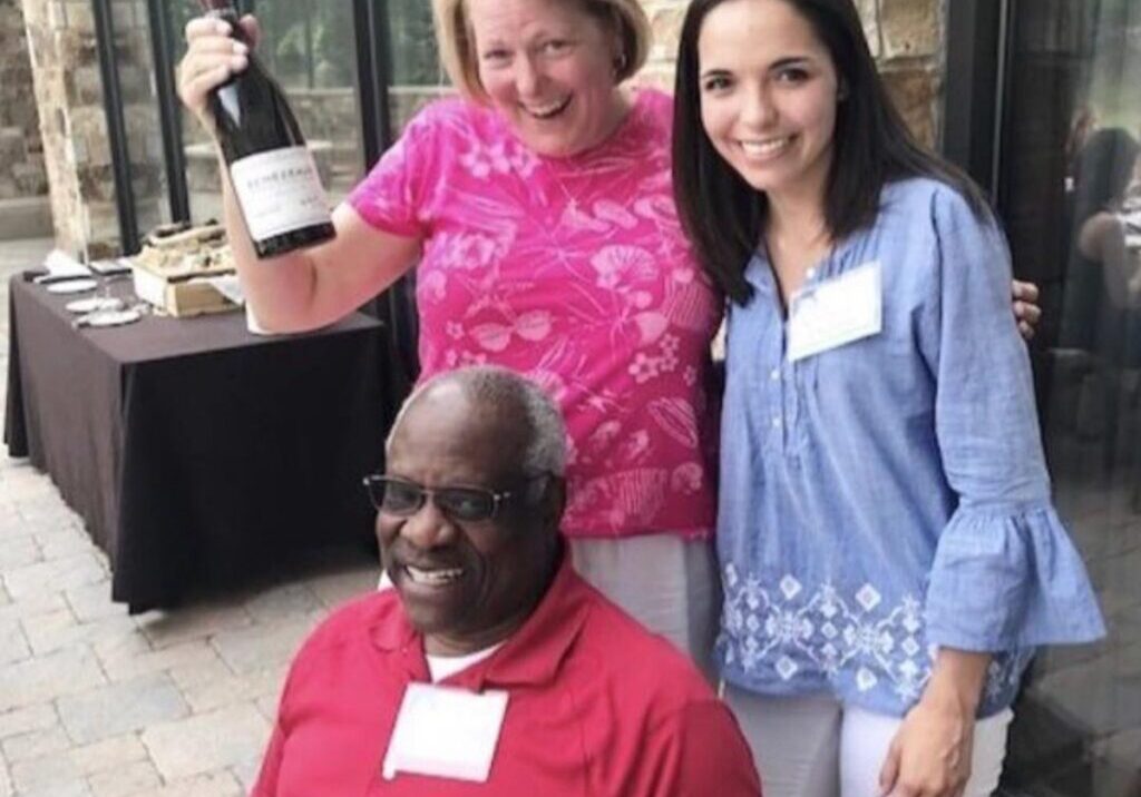 A man and two women holding wine bottles.