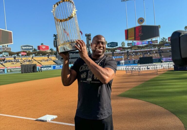 Man holding World Series trophy on baseball field.