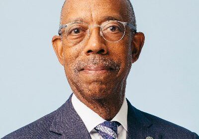 Man in suit and glasses smiling.