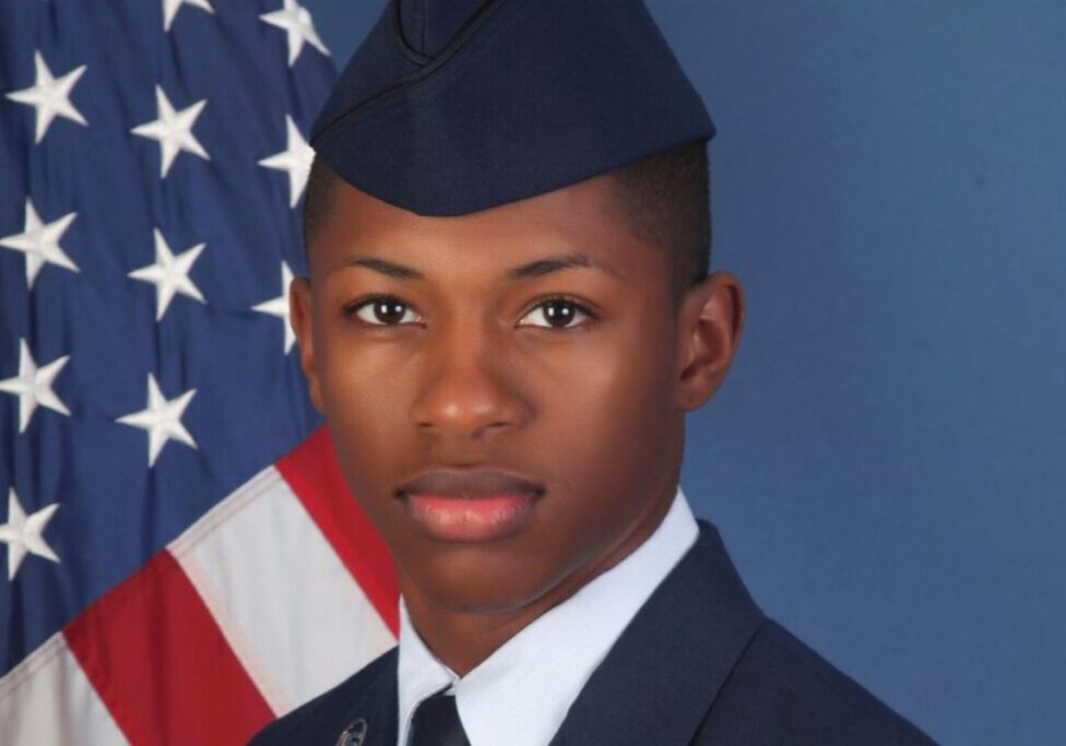 Young man in military uniform with US flag.