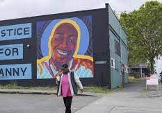 A woman walking in front of a mural on the side of a building.