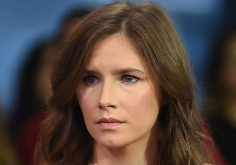 A woman with long brown hair looking serious.