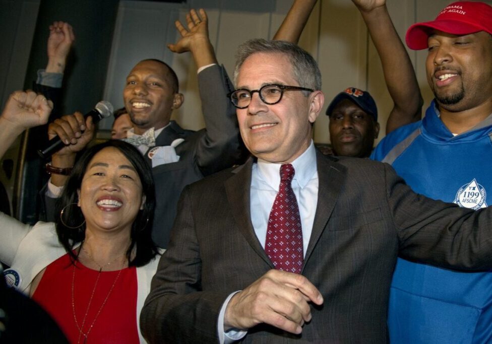 Politician in suit with supporters at rally.