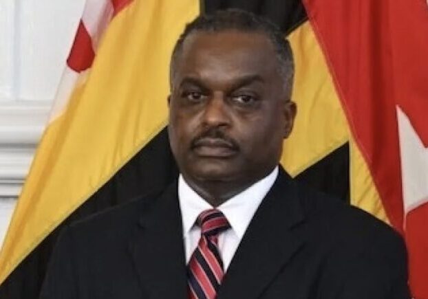 A man in a suit and tie standing next to an american flag.